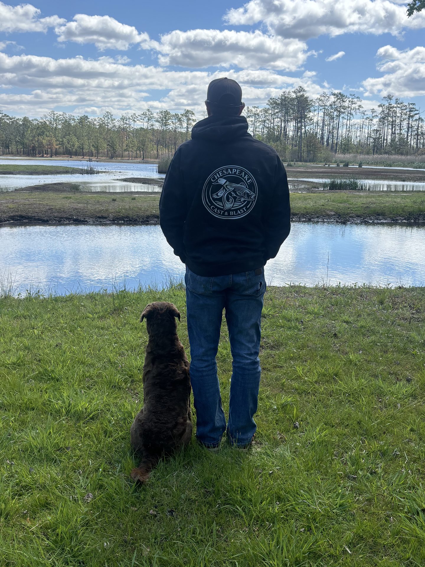 Captain and his retriever looking out over a Chesapeake marsh pond