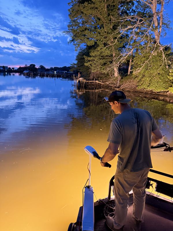 Bowfisherman on the shooting deck as light fades over a Maryland creek