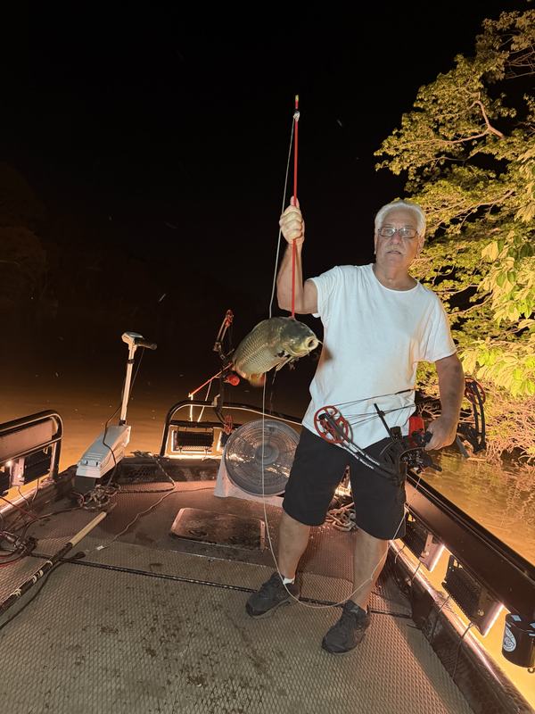 Guest holding a carp taken by bow at night