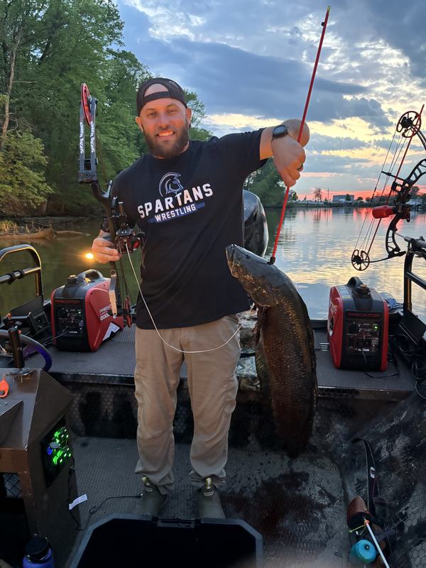 Bowfisherman holding a snakehead at sunset