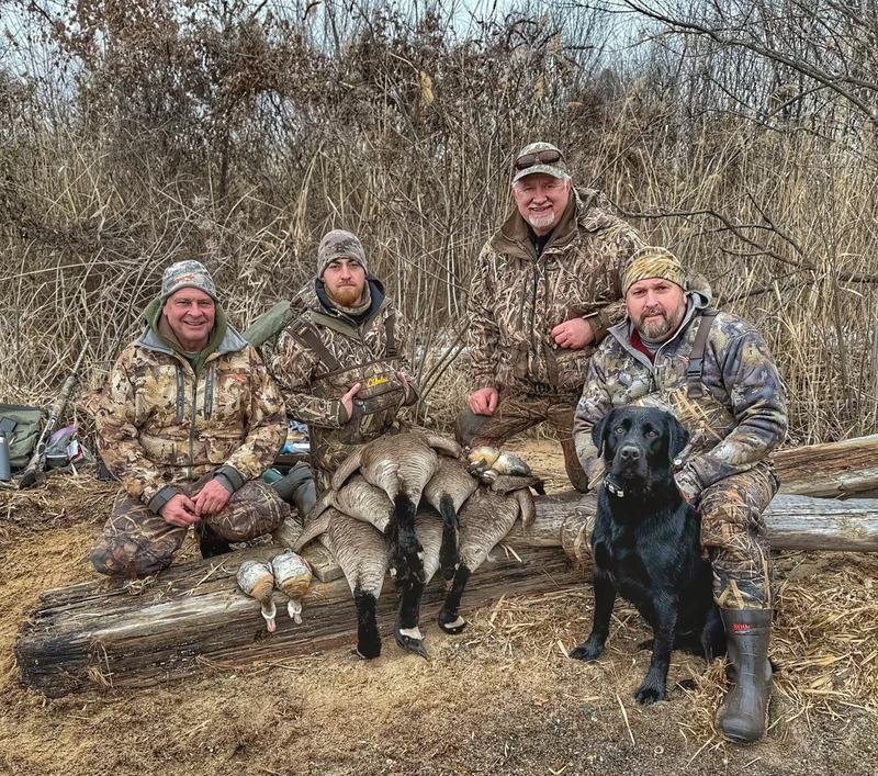 Four hunters and a retriever behind a morning's ducks